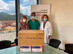 Tres professionals sanitaris amb mascaretes posant amb caixes de xeringues donades a l'Hospital Sant Celoni