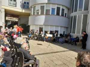 Concert musical en viu al pati d'una residència amb músics i públic assegut gaudint de l'actuació a l'aire lliure