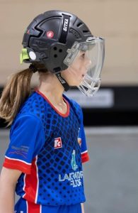 Jugadora de hoquei patins amb casc protector i uniforme blau durant un partit o entrenament esportiu