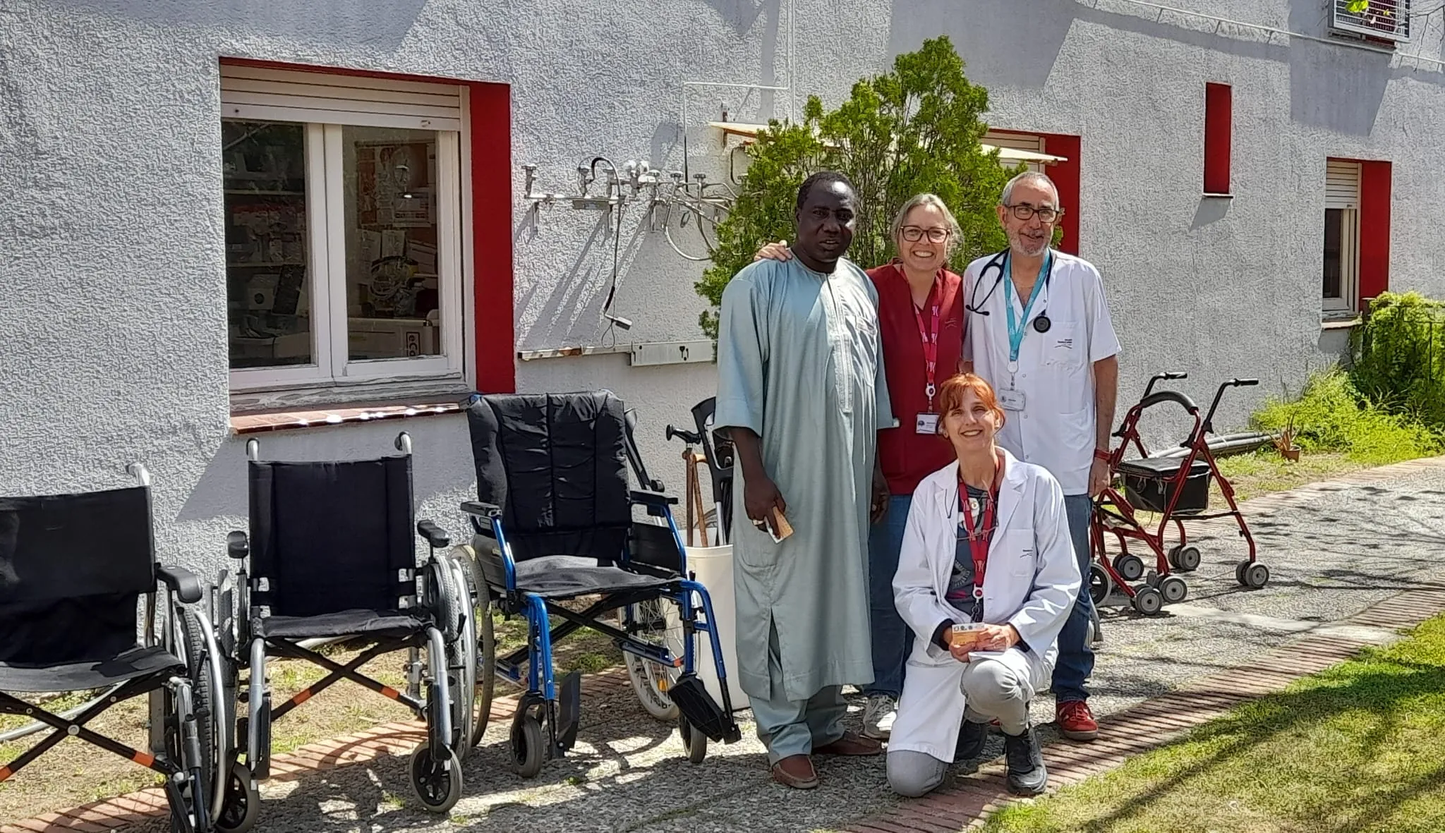 Professionals sanitaris posant amb cadires de rodes i equips mèdics davant d'un centre de salut amb façana blanca