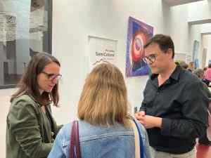 Tres persones conversant en un hospital, amb banners de l'Hospital Sant Celoni visibles al fons de la sala.