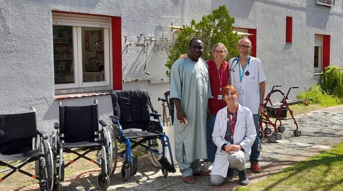 Professionals sanitaris posant amb cadires de rodes i equips mèdics davant d'un centre de salut amb façana blanca