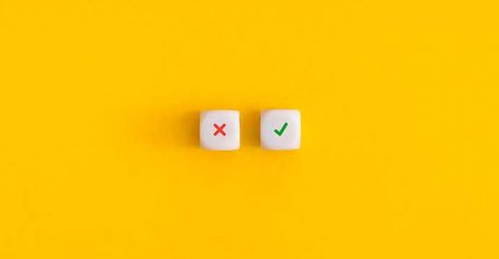 Cross and check mark on a white cubes on yellow background. Approving, voting or right decision concept.
